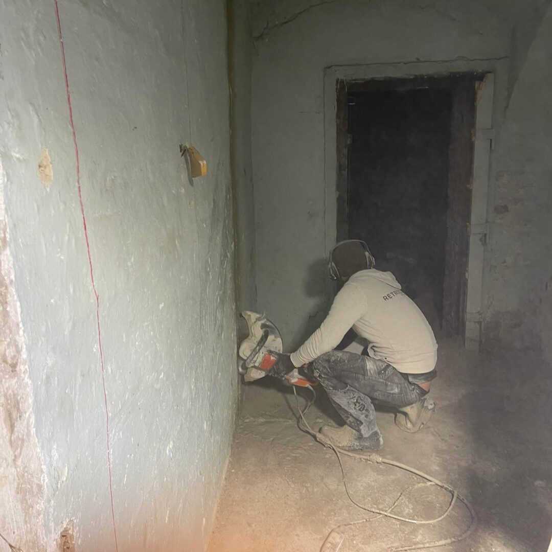 ProCut szakember betonfalat vág kézi ipari vágógéppel egy épület belső terében, kivitelezés közbeni munkafolyamat.