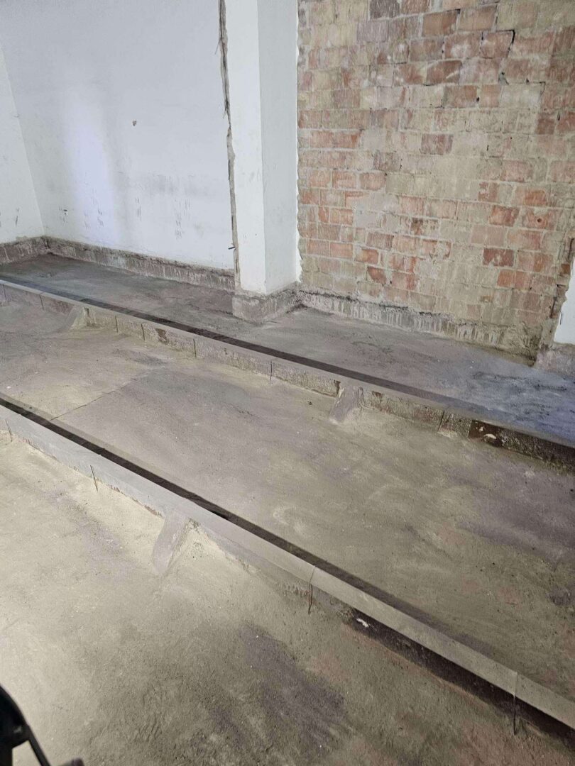 Bontási munkálatok utáni padlószakasz, ipari betonvágás nyomaival, téglafal és simított vakolt fal előtt, ProCut kivitelezés után.