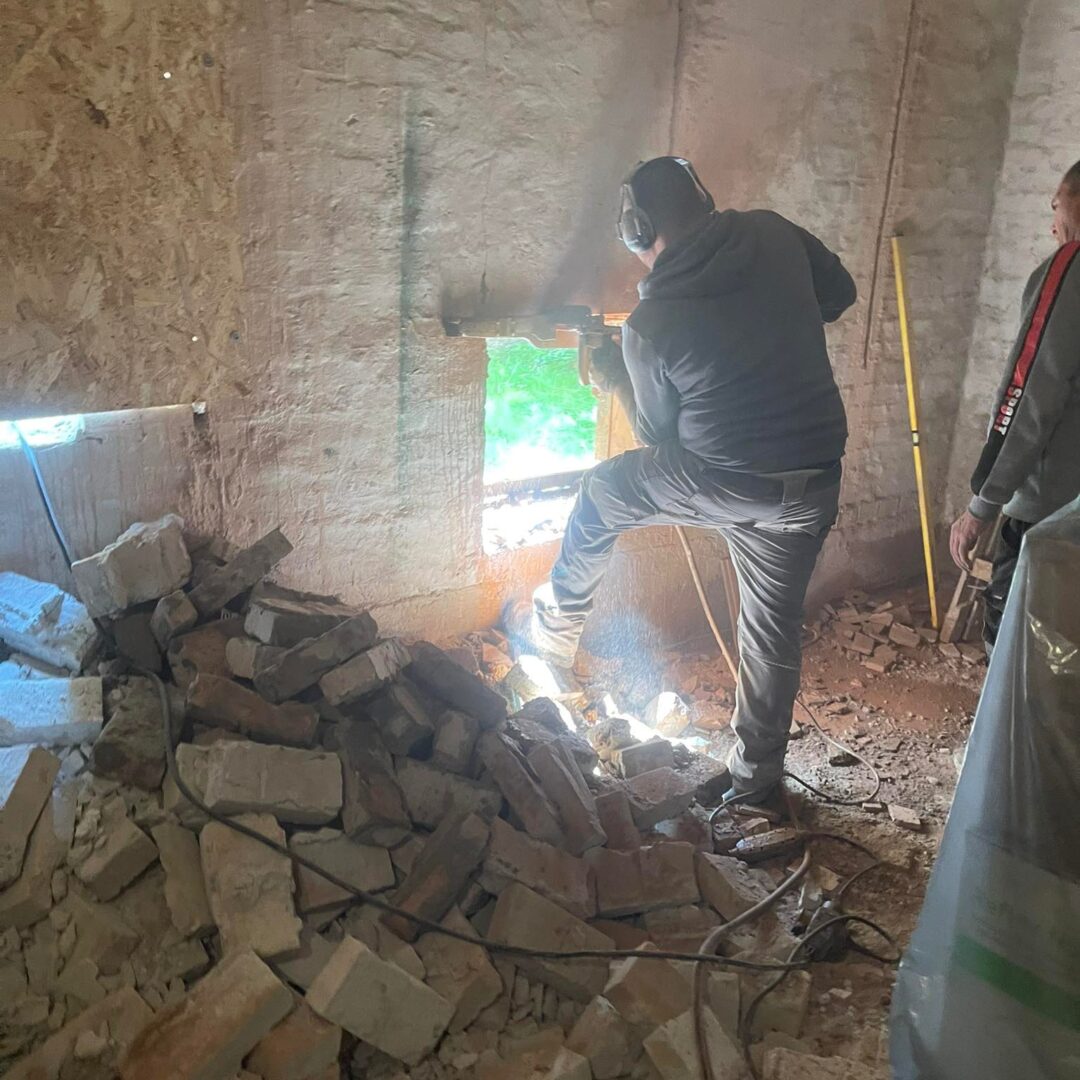 ProCut szakember új ablaknyílást vág tégla falban ipari géppel, bontási törmelékkel és szikrázó munkafolyamat közben.