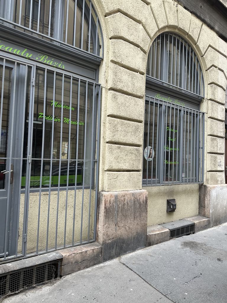 Falvágás előtt kialakított üzletportálok klasszikus városi homlokzaton, ProCut kivitelezés előtt, új nyílászárókkal és acélrácsozással.